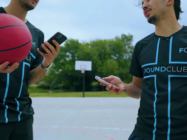 Sur le terrain de basket, un téléphone dans une main, le ballon dans l'autre